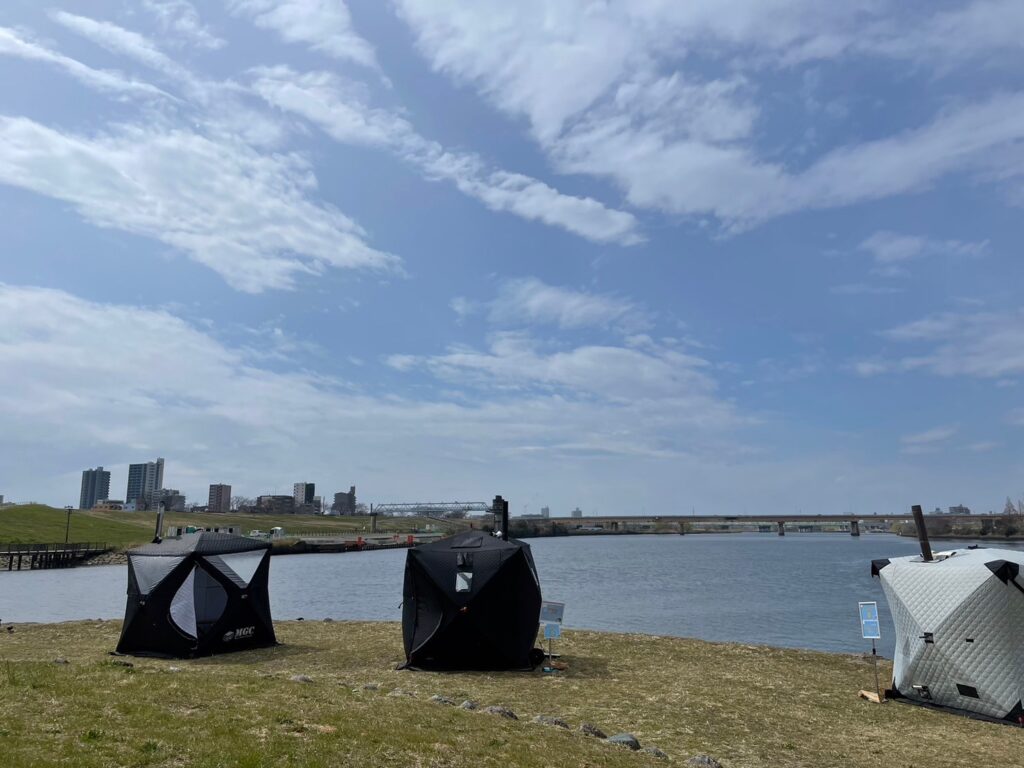 荒川河川敷で開催されたアウトドアサウナイベントの様子。広々とした空の下、テントサウナが設置されている。