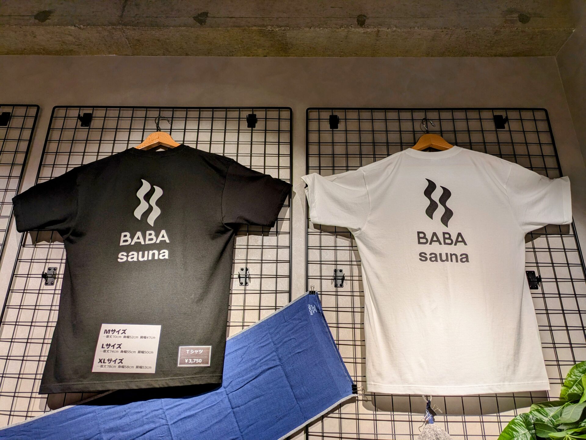 BABA saunaのオリジナルTシャツ。黒と白の2色があり、胸元にはBABA saunaのロゴがプリントされている。価格は3,750円。