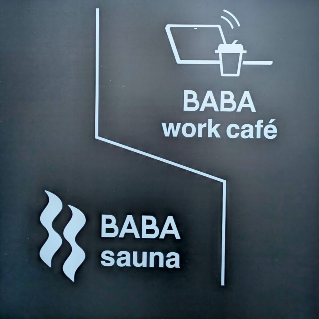 BABA saunaとBABA work cafeの場所を示す案内看板。上はノートPCとコーヒーのイラストでワークカフェ、下は湯気のイラストでサウナを表している。