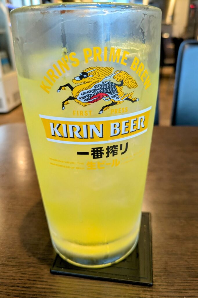 グラスに注がれた「オロポ」。グラスにはKIRIN一番搾りのロゴが描かれている。グラスの表面には水滴がついており、冷えていることがわかる。テーブルに置かれた黒いコースターの上にグラスが乗っている。