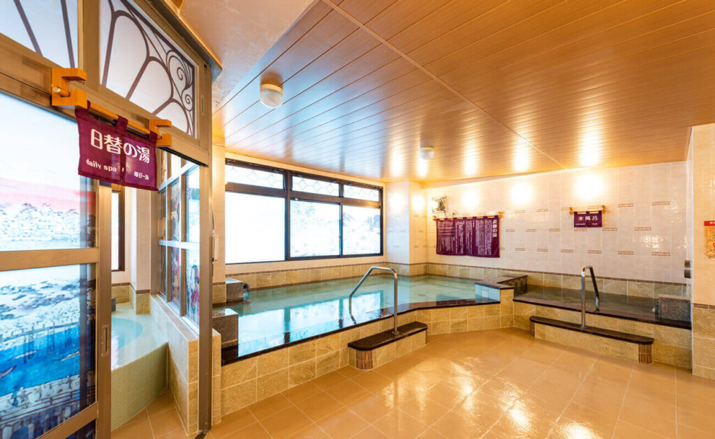 RAKU SPA 1010 神田の内湯。広々とした温浴槽と日差しが差し込む明るい浴室。