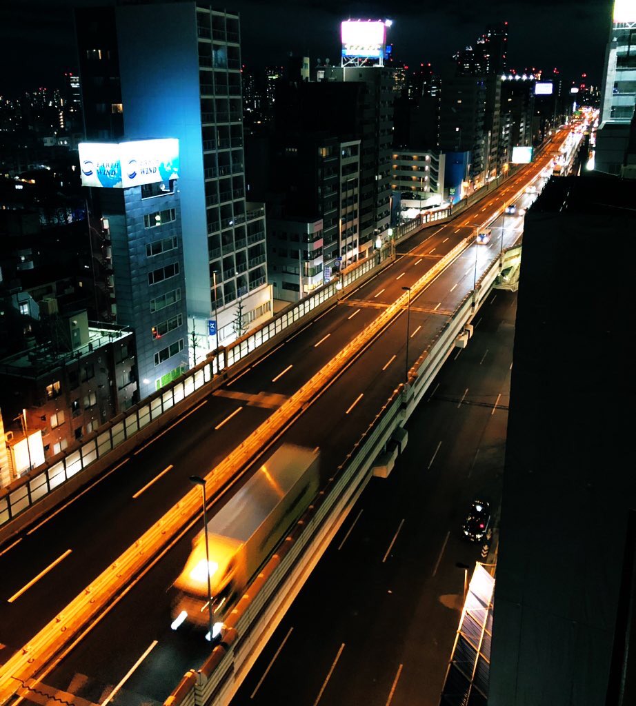 東京都渋谷区笹塚の首都高速道路4号新宿線と甲州街道の夜景。ビルの谷間を走る高速道路と、その下を走る甲州街道を、多くの車がライトを照らしている。遠くにはビル群の明かりが広がっている。
