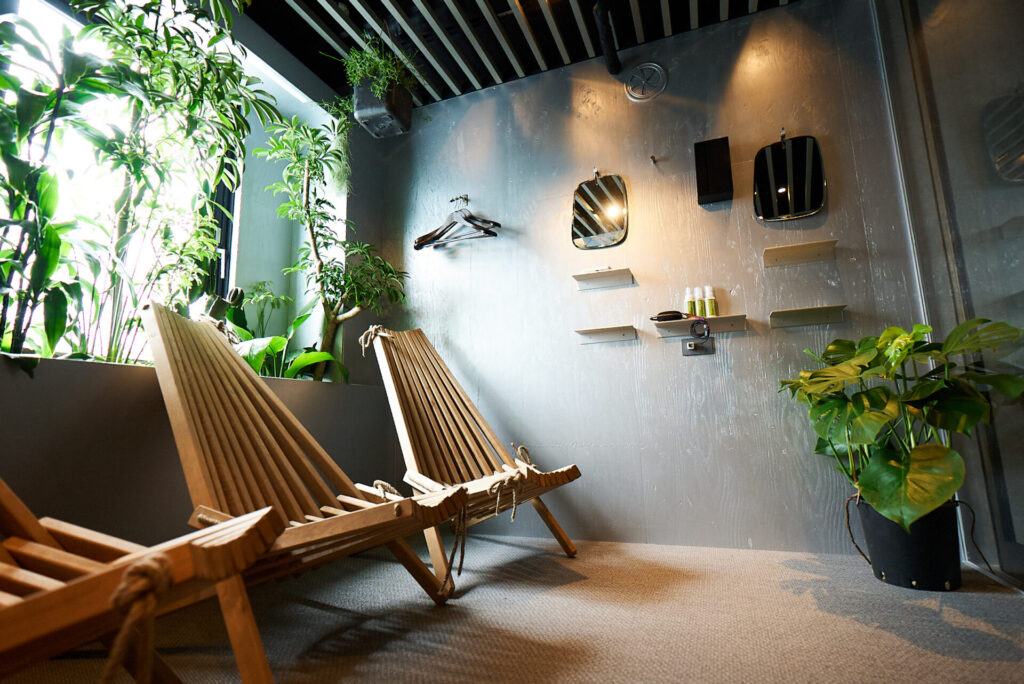 sauna&co(サウナアンドコー)のととのいスペース。観葉植物と2つの木製チェアが並び、落ち着いた雰囲気の内装。